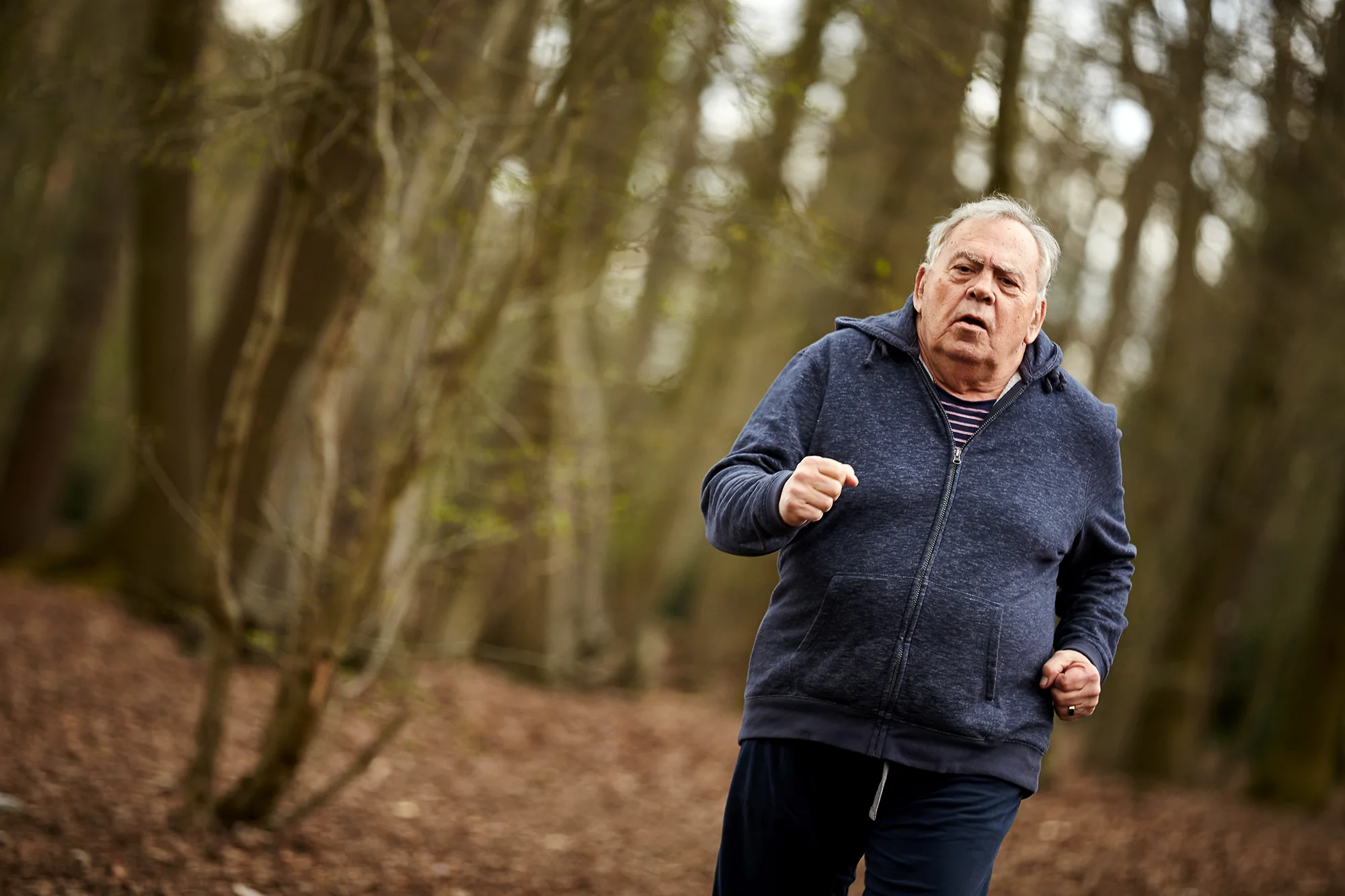 Elderly man jogging in woods