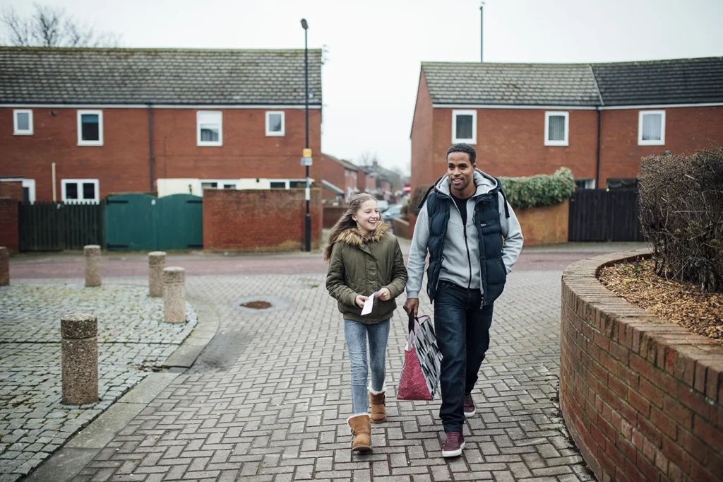 Man and daughter outside houses