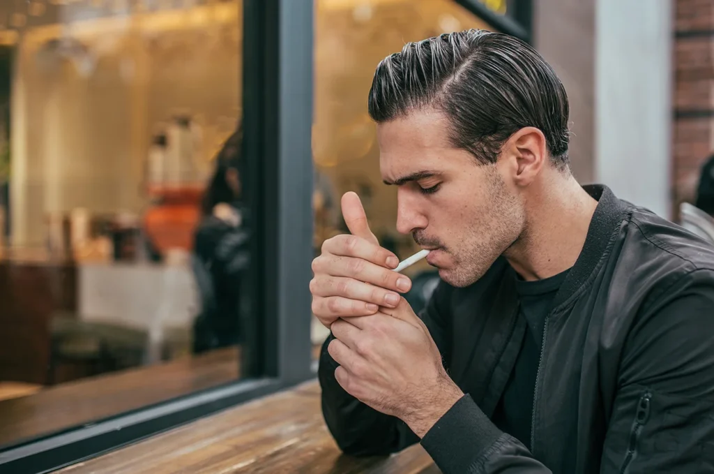 Man in leather jacket lighting a cigarette
