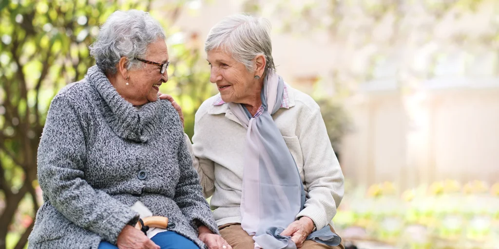 Two older ladies smiling on a bench