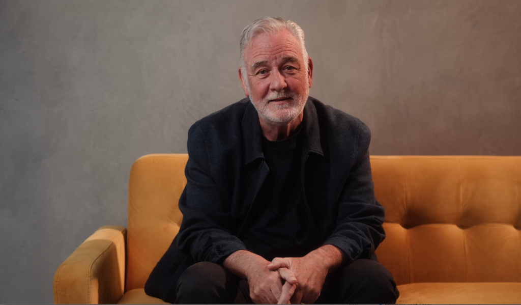 A man sitting on a sofa, looking to camera